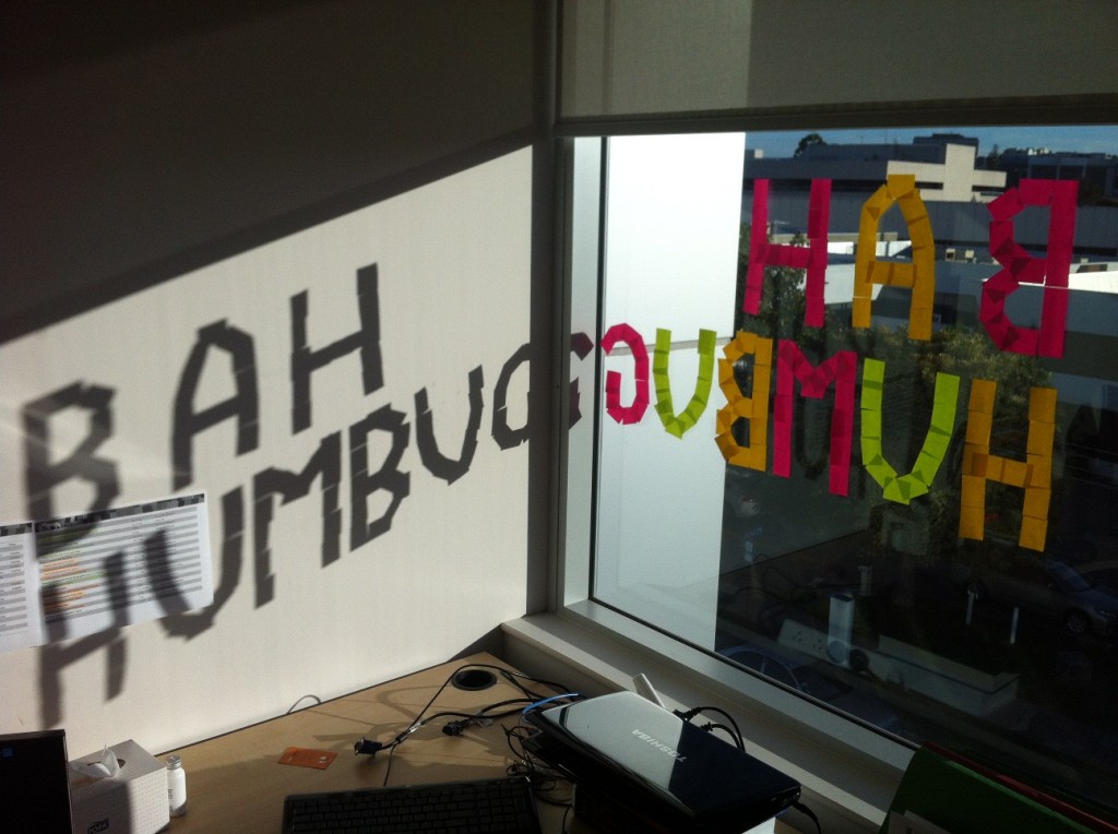 BAH HUMBUG is spelt out onto the window in Post-It notes; it also casts a shadow on the wall.